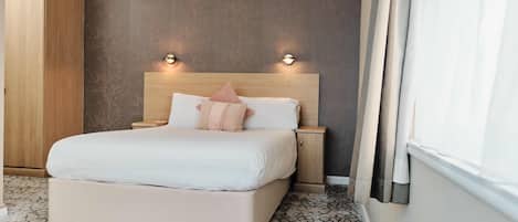 Un dormitorio con una cama grande, una mesita de noche, un armario de madera y un aplique de pared.