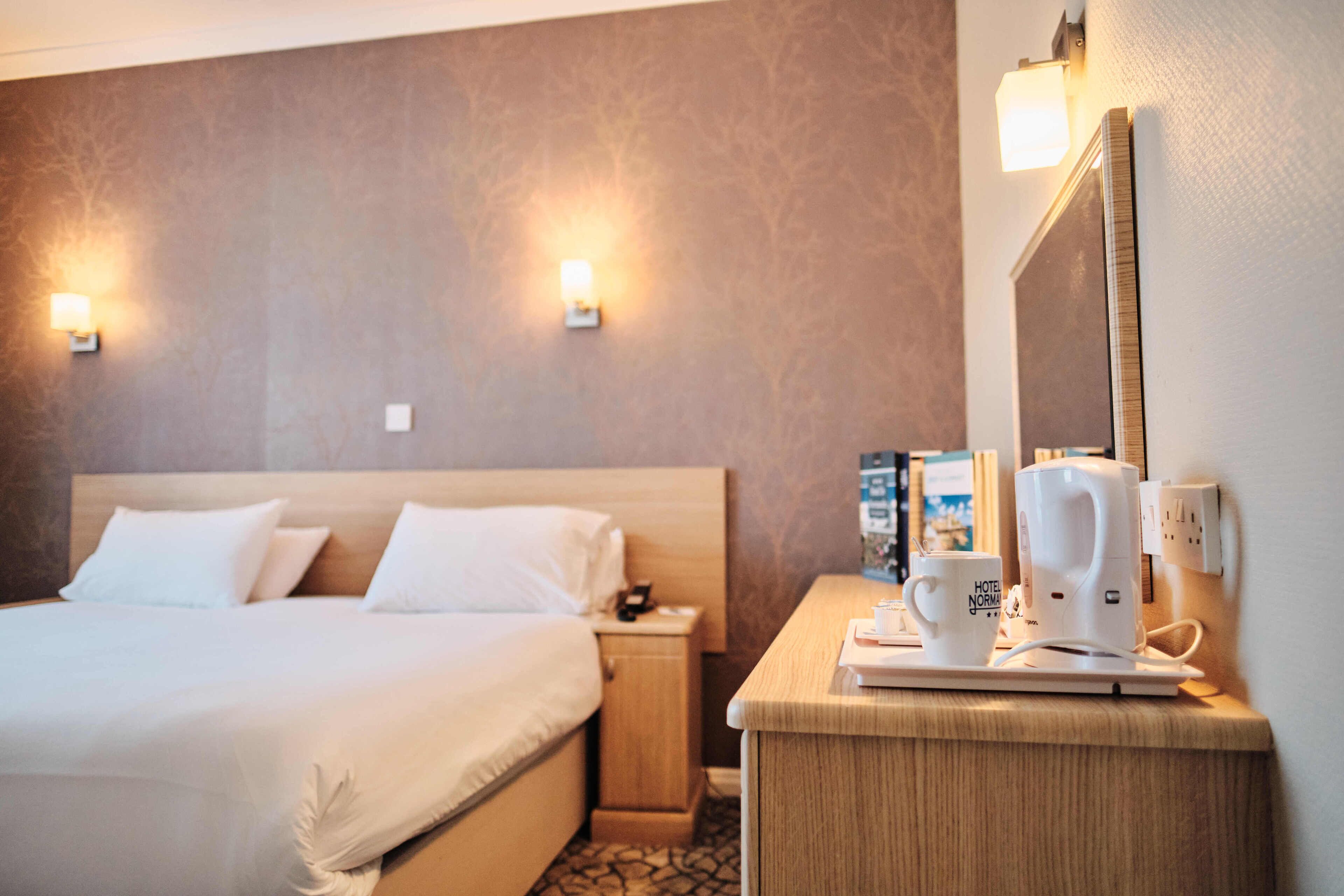 Et hotelværelse med en seng, et sengebord og en kaffemaskine.