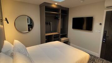 Habitación de hotel con una cama grande, tragaluz, vestidor, televisor y alfombra estampada.