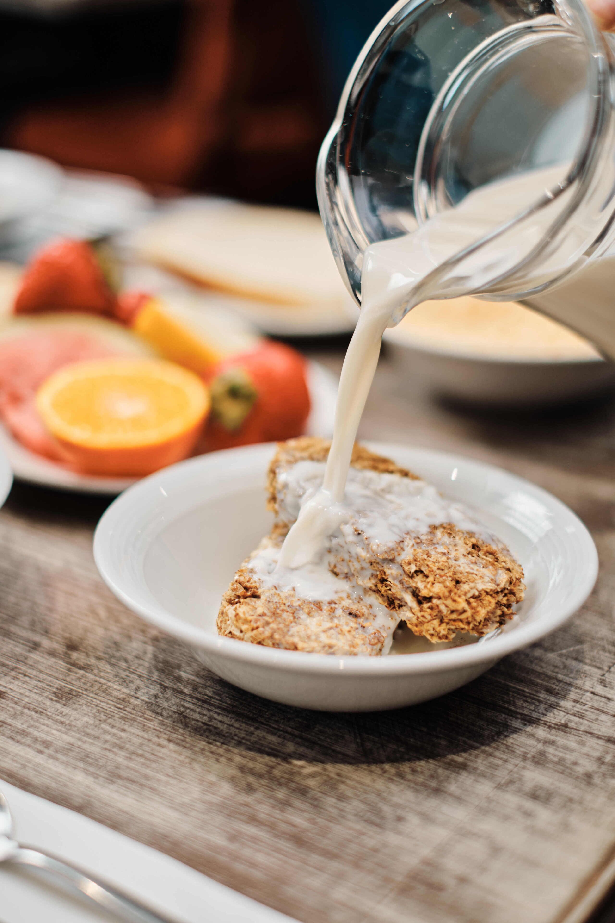 A breakfast scene with a plate of toast and a glass of milk being poured.