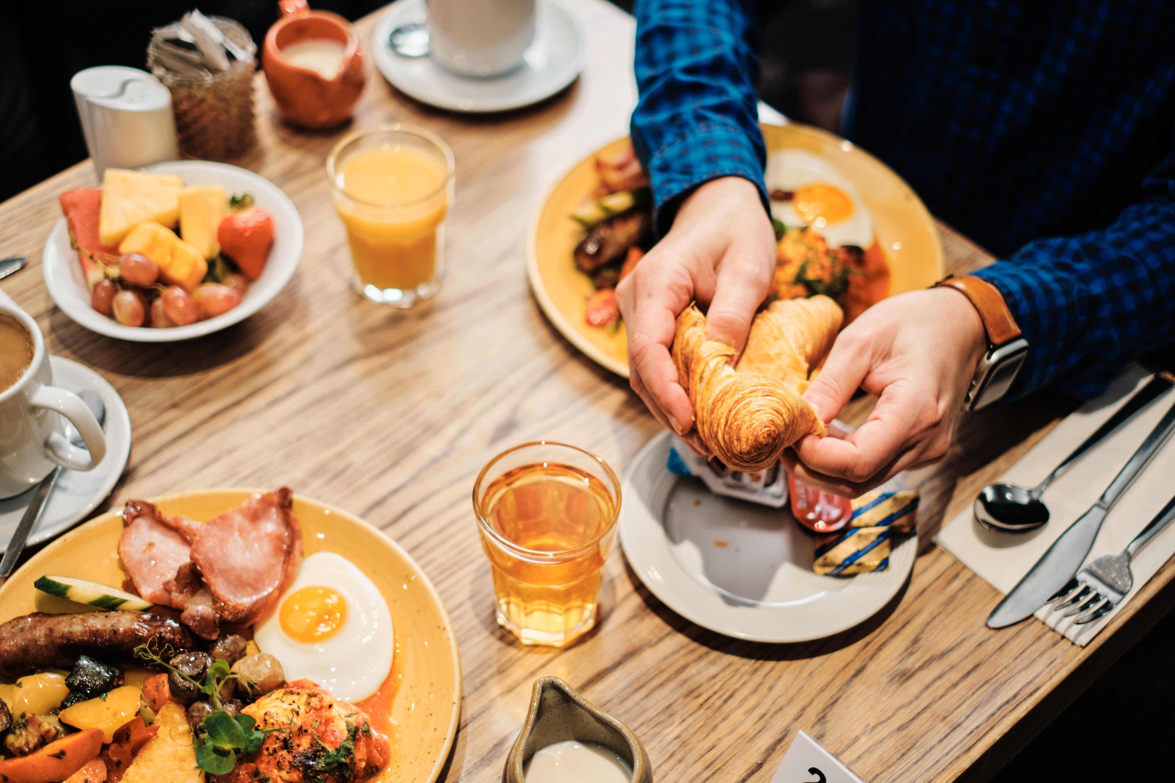 A breakfast setting with plates of food, a glass of juice, and a cup of coffee.