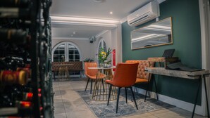 A modern dining area with a round table, orange chairs, and a sofa. - Le Pommier (Castel)