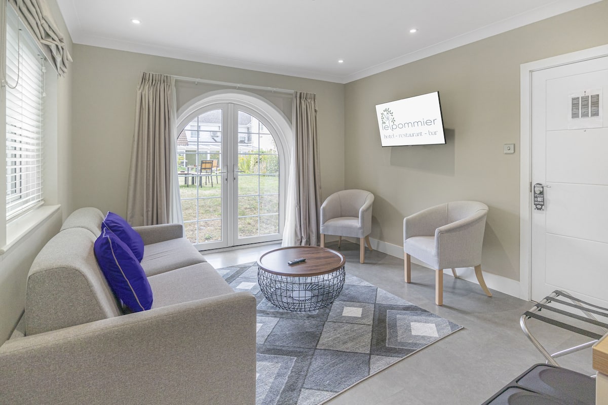 Una sala de estar moderna con un sofá, dos sillones, una mesa de centro y un televisor montado en la pared.