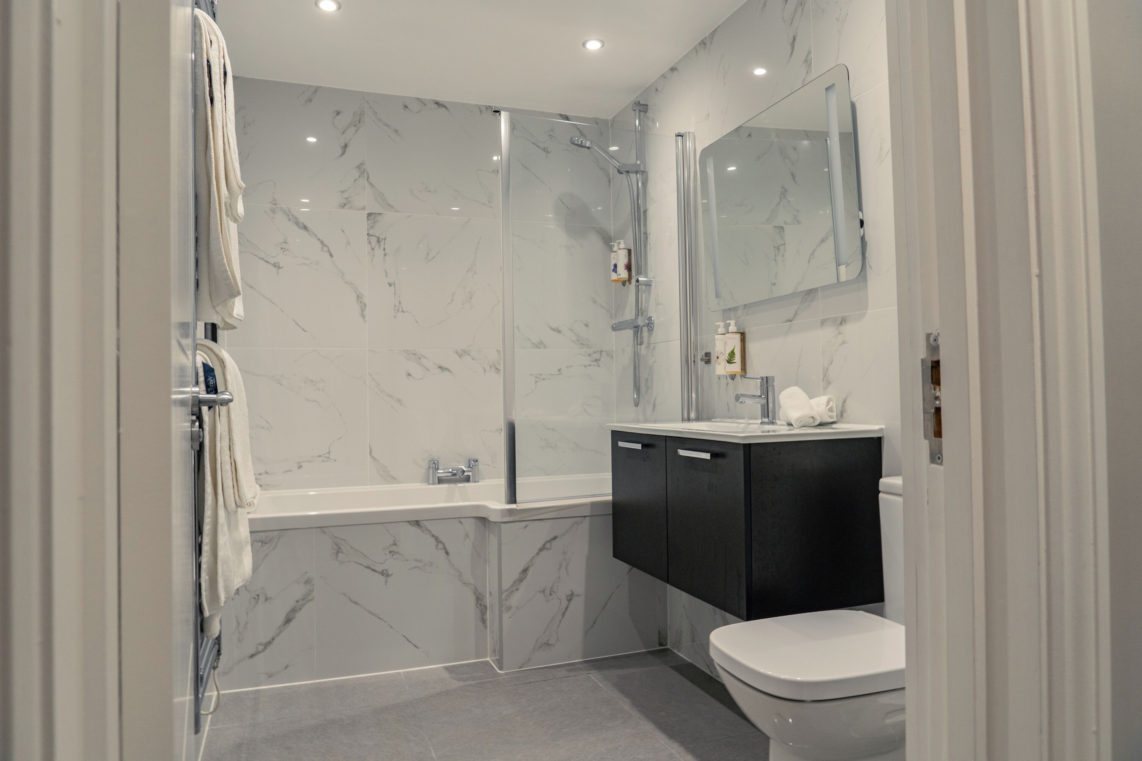 Une salle de bain avec une douche à parois de verre, des toilettes et un meuble-lavabo avec un miroir.