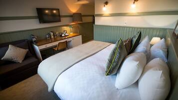 A hotel room with a bed, a desk, a chair, a TV, and a couch.
