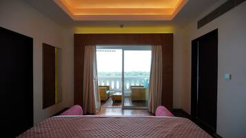 A hotel room with a large bed, a balcony with a view, and a sliding door.
