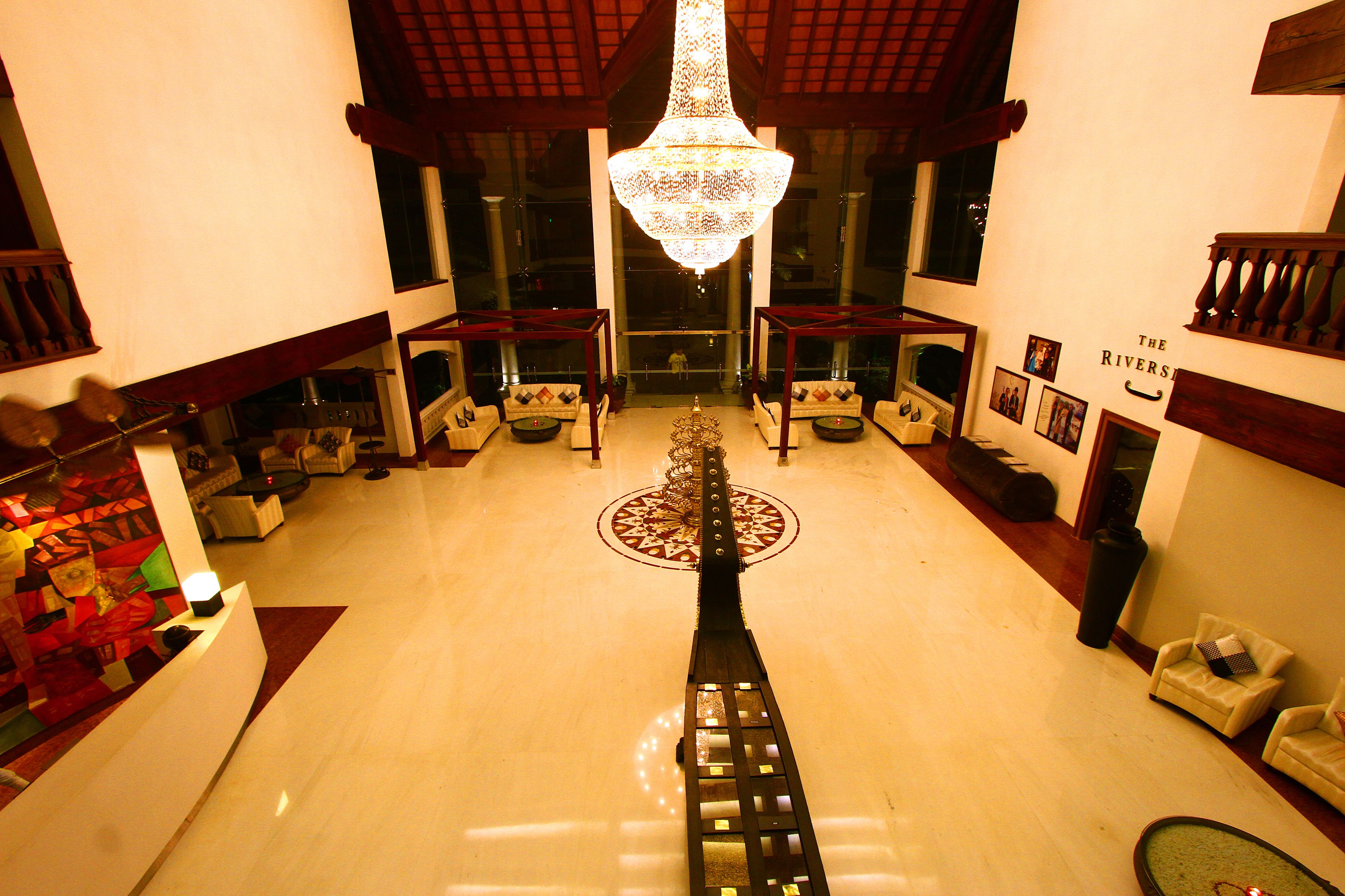 Un vestíbulo con candelabro, sofás, un mostrador de recepción y una pared con el letrero 'The Rivers'.