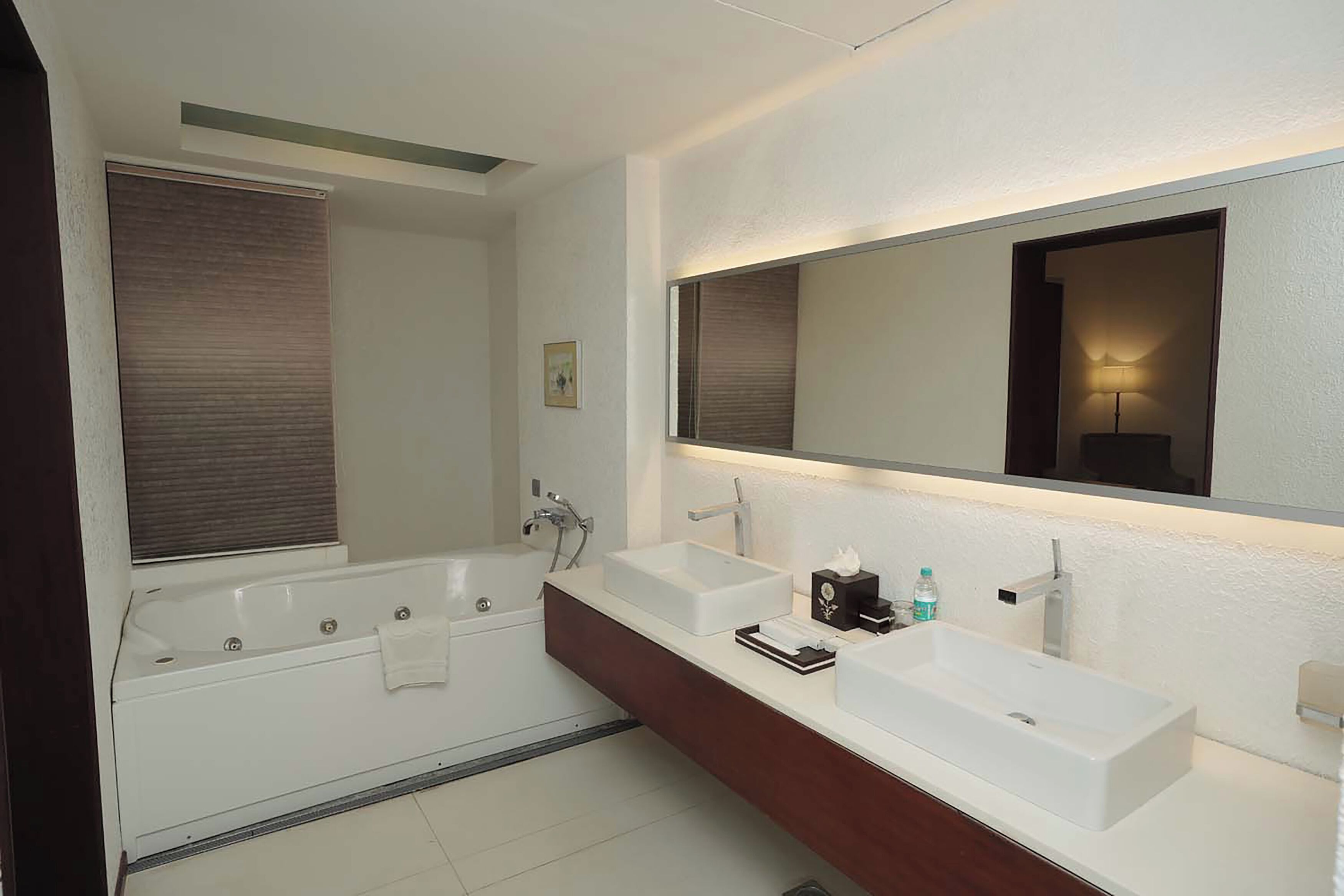 Un baño moderno con bañera, dos lavamanos, un espejo grande y un perchero para toallas.