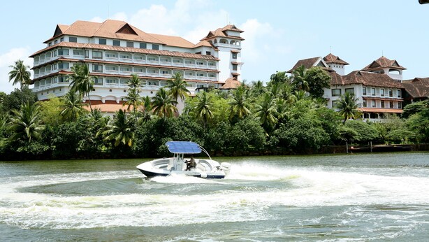 A large resort hotel with multiple balconies and a water body in front.