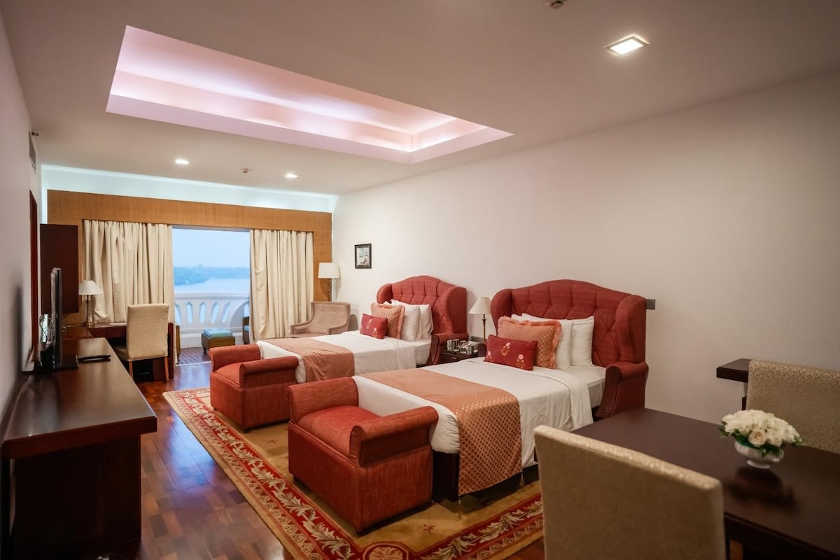 Habitación de hotel con dos camas, un escritorio, una silla y vista al mar.