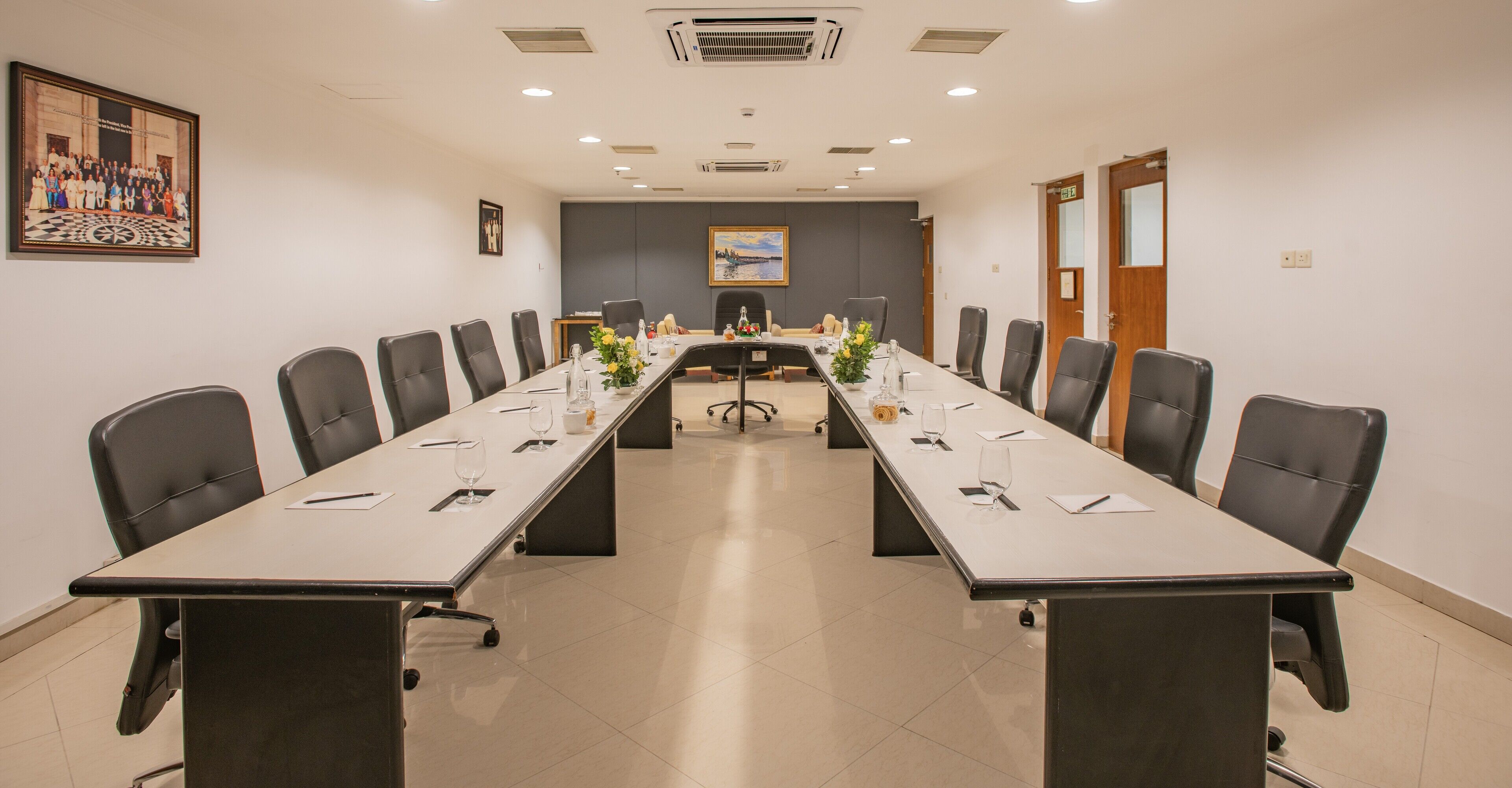 A conference room with a long table, chairs, and a painting on the wall.