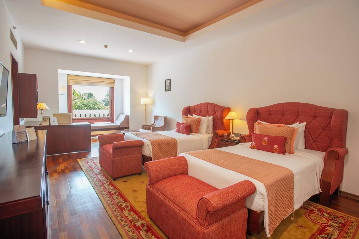 A hotel room with two beds, a desk, and a chair.
