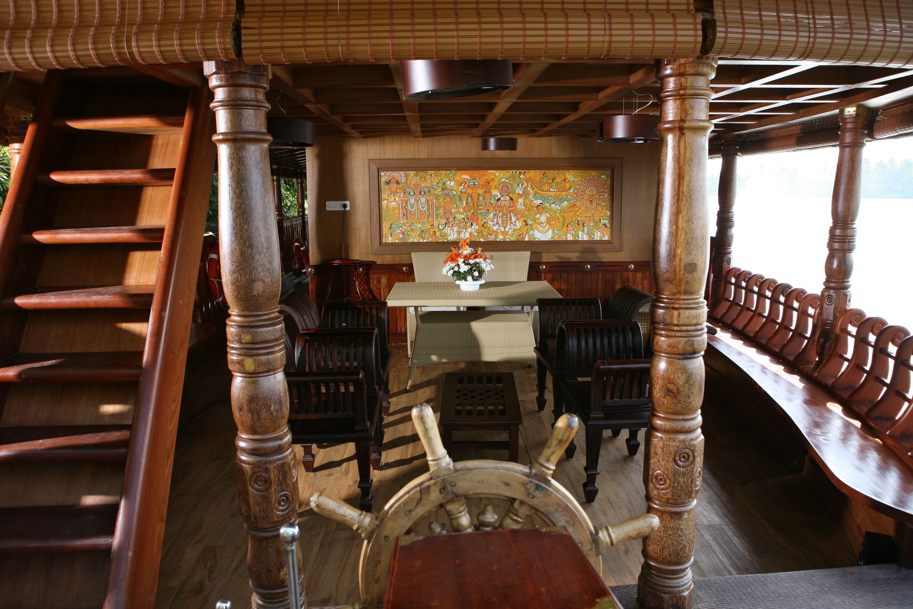 Un interior de madera con una rueda de barco, un mural grande y una zona de comedor con mobiliario de madera.