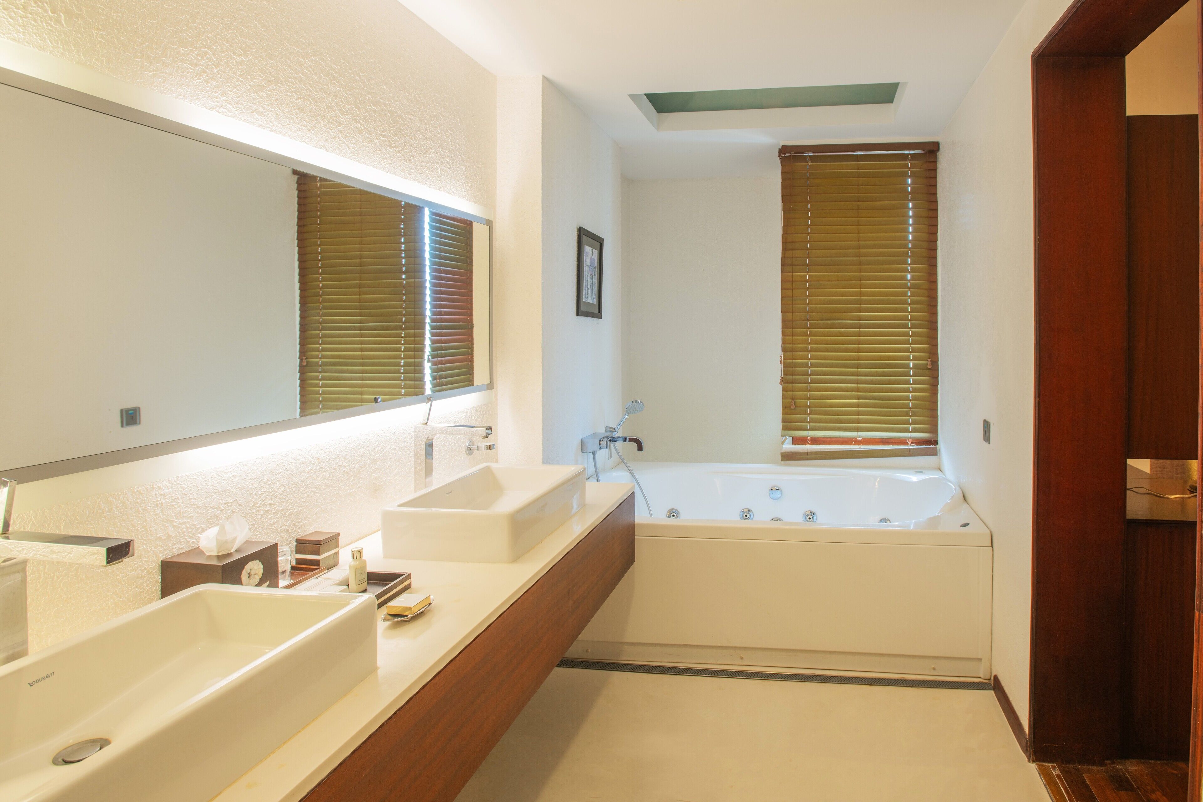 A bathroom with two sinks, a bathtub, and wooden cabinetry.