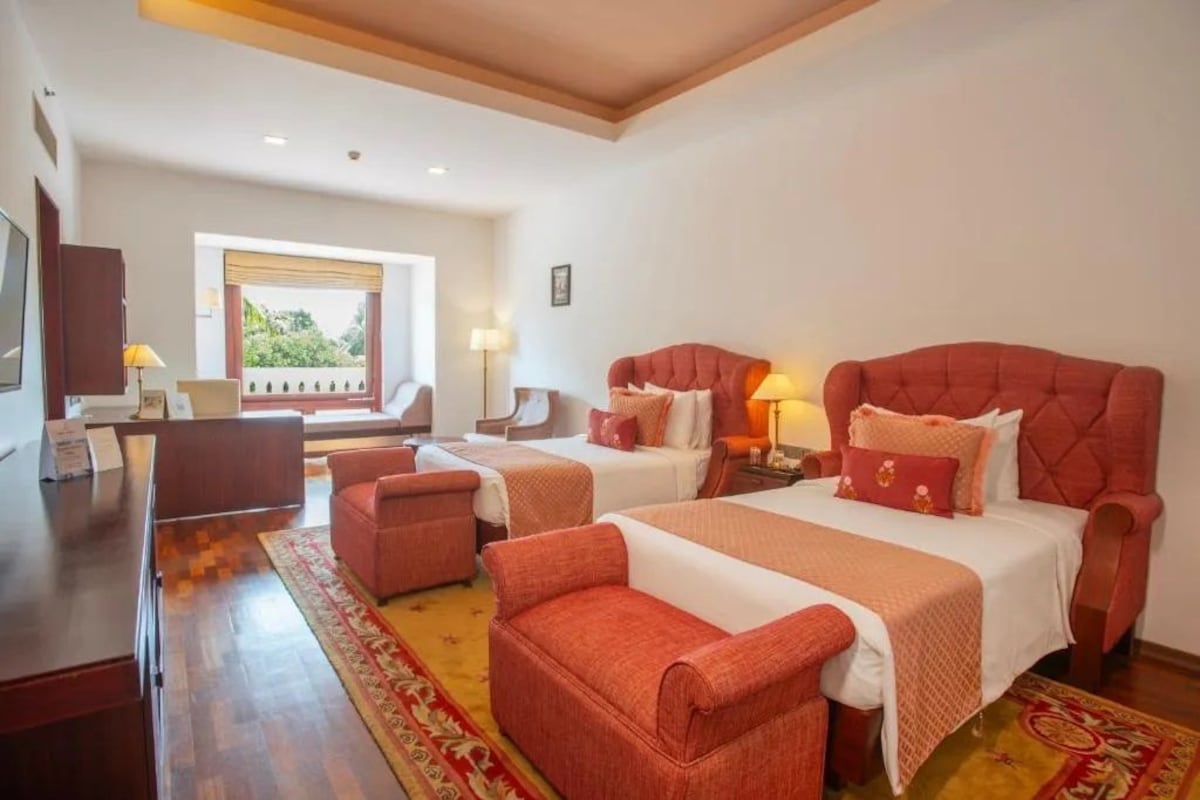 Habitación de hotel con dos camas, un escritorio y una silla.