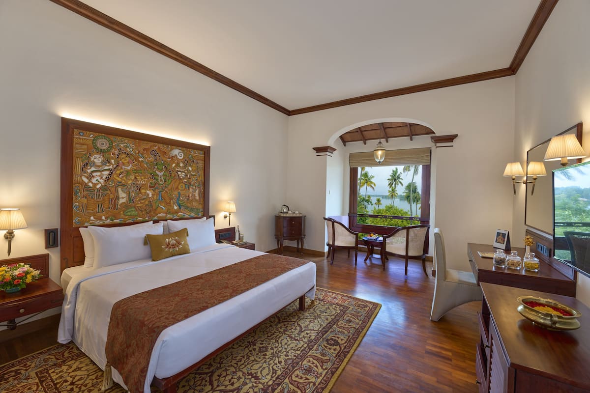 A hotel room with a large bed, a desk, and a view of palm trees.