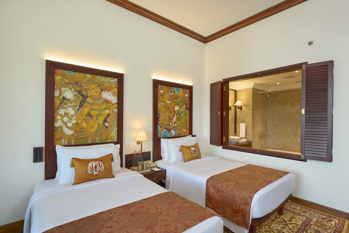 A hotel room with two beds, a large mirror, and artwork on the walls.
