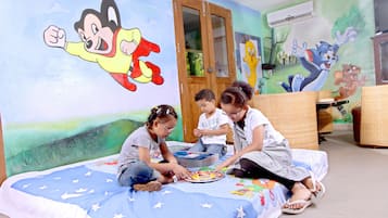 Cozy retreat with a large bed, colorful cartoon character murals, and a wicker chair.