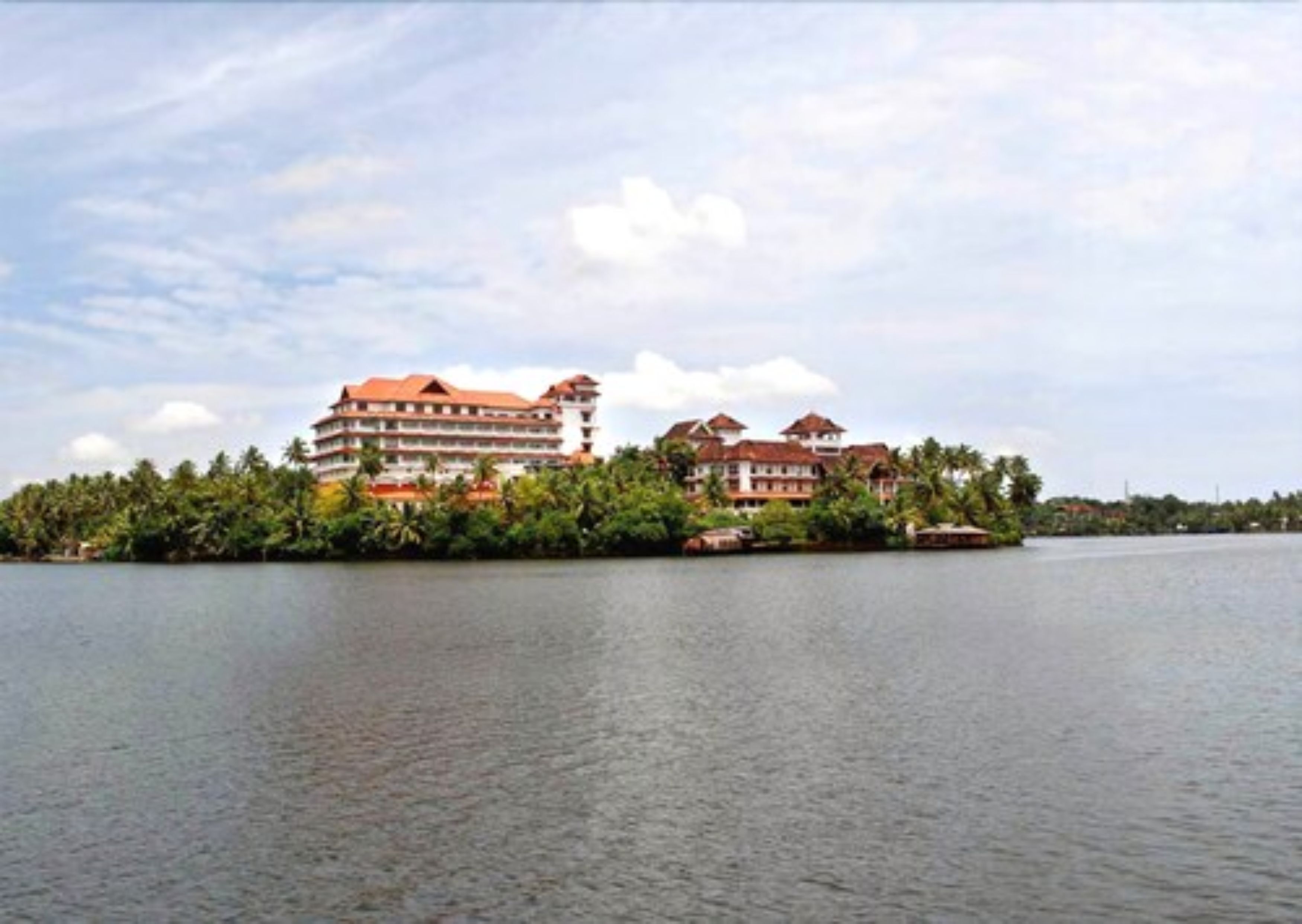 Een groot resort met meerdere gebouwen, een waterpartij op de voorgrond en een tropisch landschap met weelderige begroeiing.