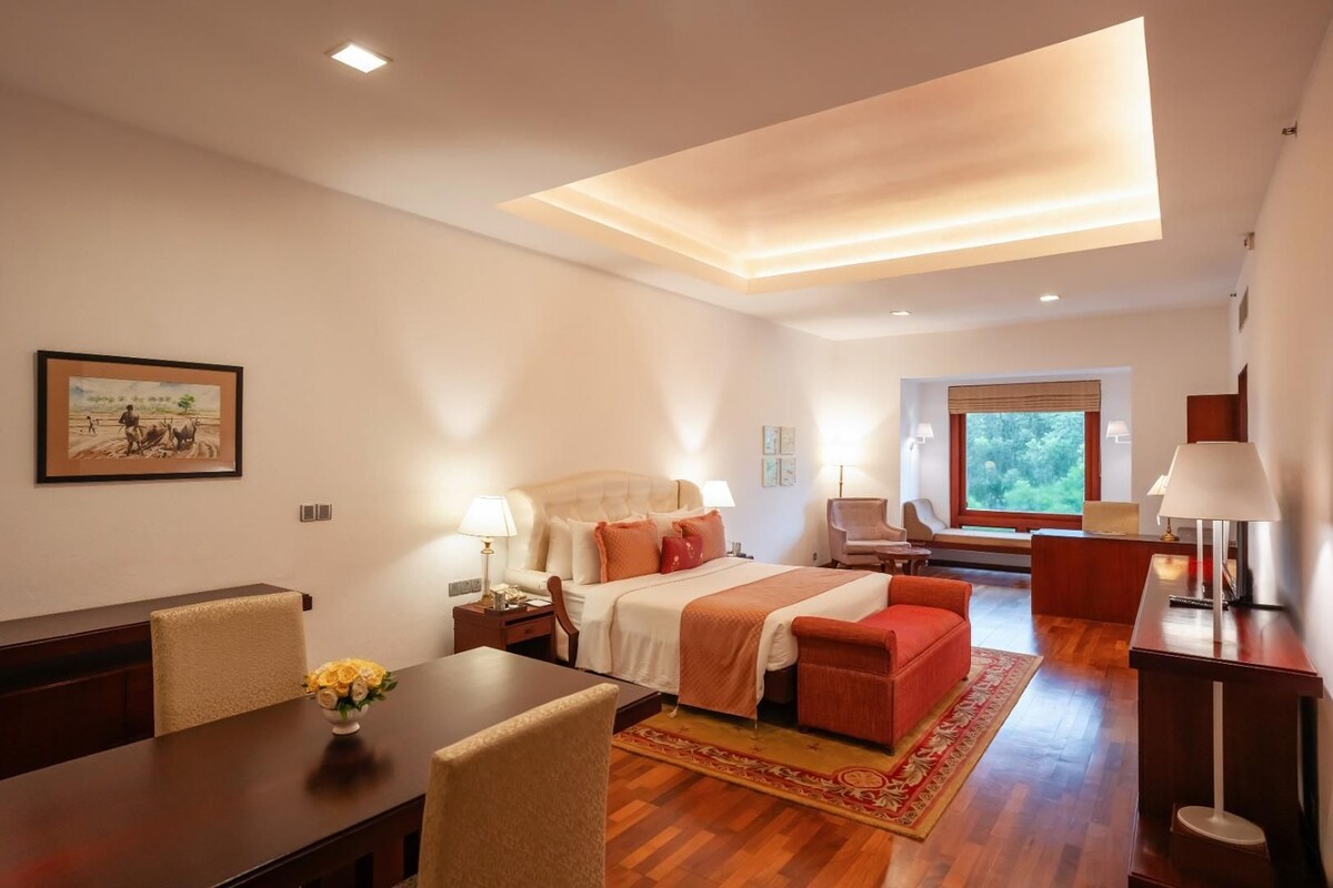 Habitación de hotel con cama, escritorio, silla, sofá, ventana y un cuadro en la pared.