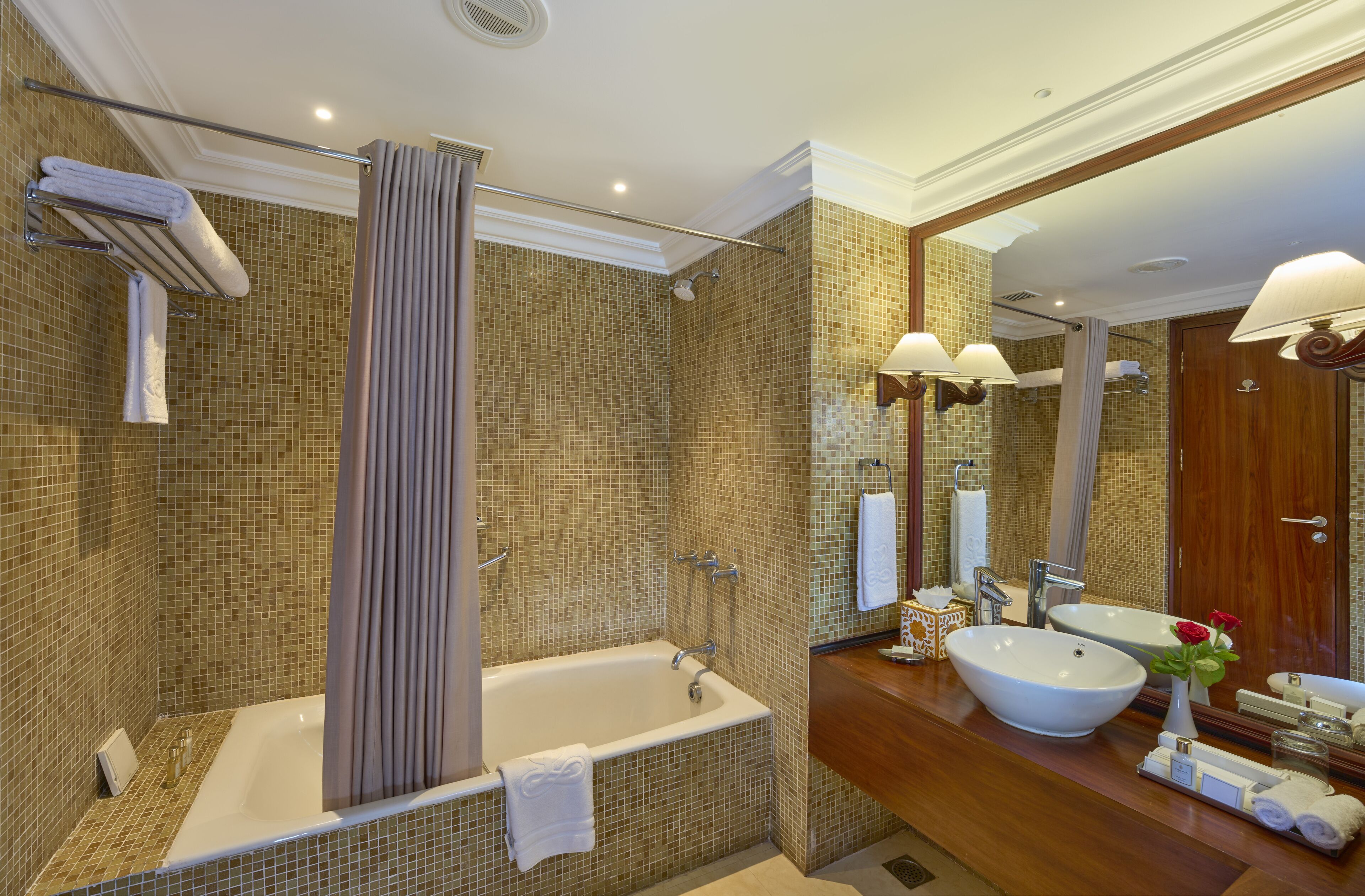 A modern bathroom with a freestanding bathtub, a large mirror, a sink with a vessel basin, and a shower area with a curtain.