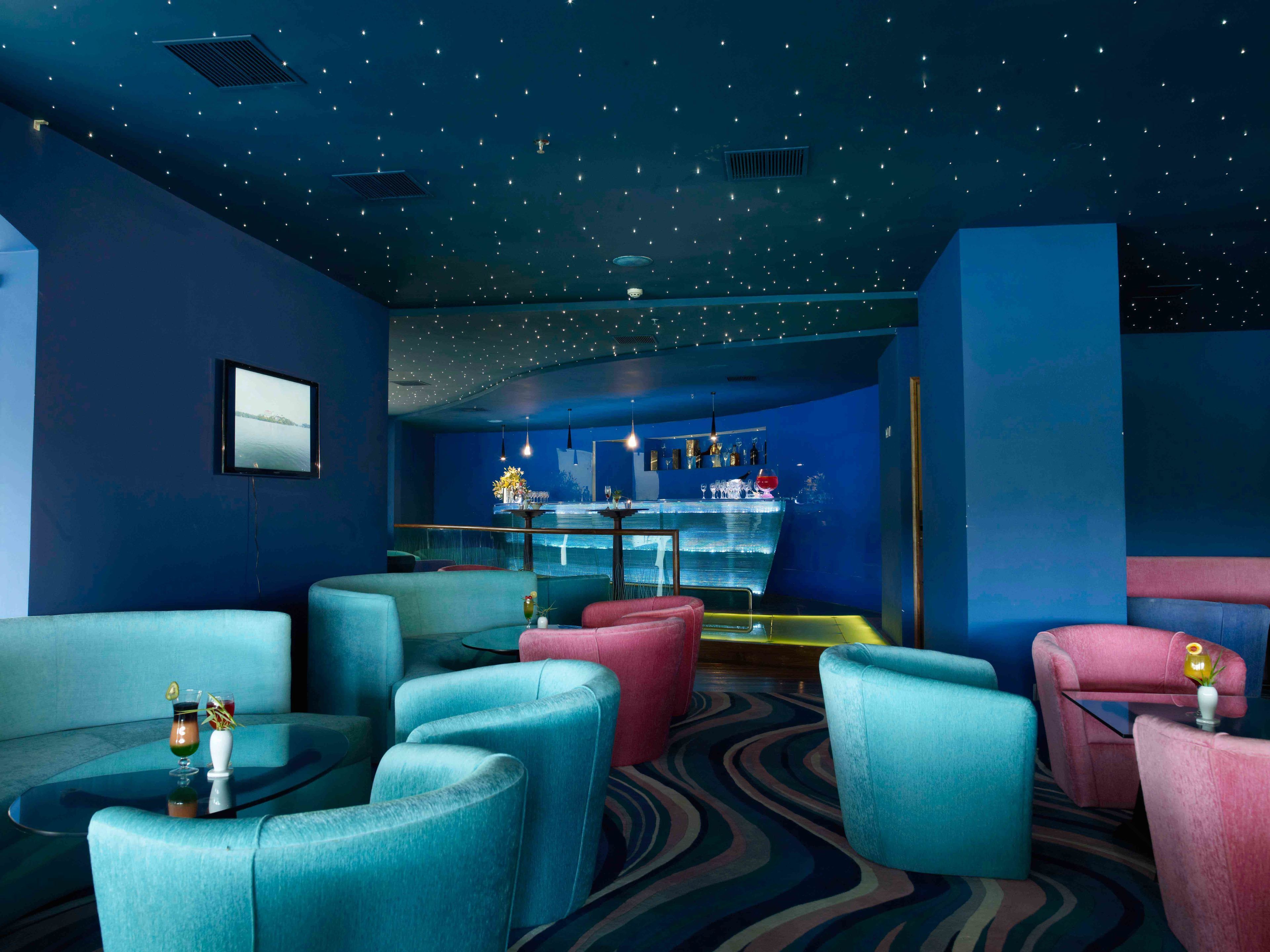 A room with a starry ceiling, a bar area, and seating with a view of the bar.