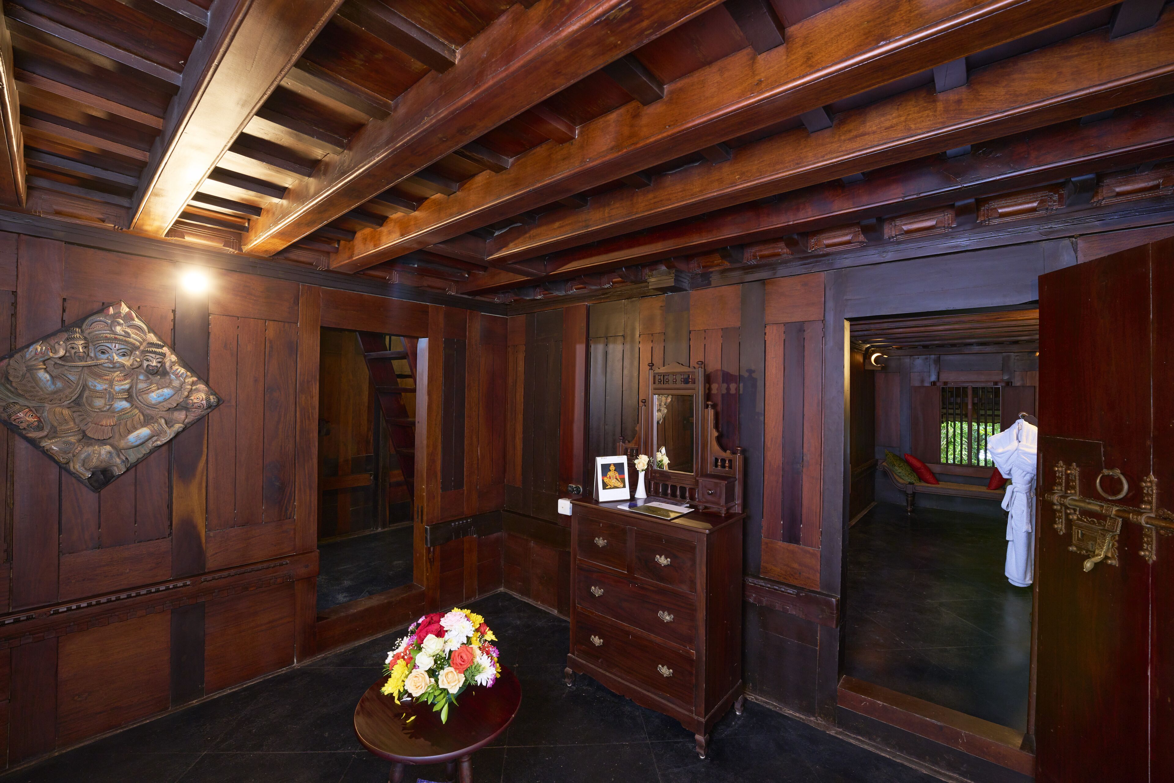 Un interno in legno con un comò di legno, uno specchio e un bouquet di fiori su un tavolo.