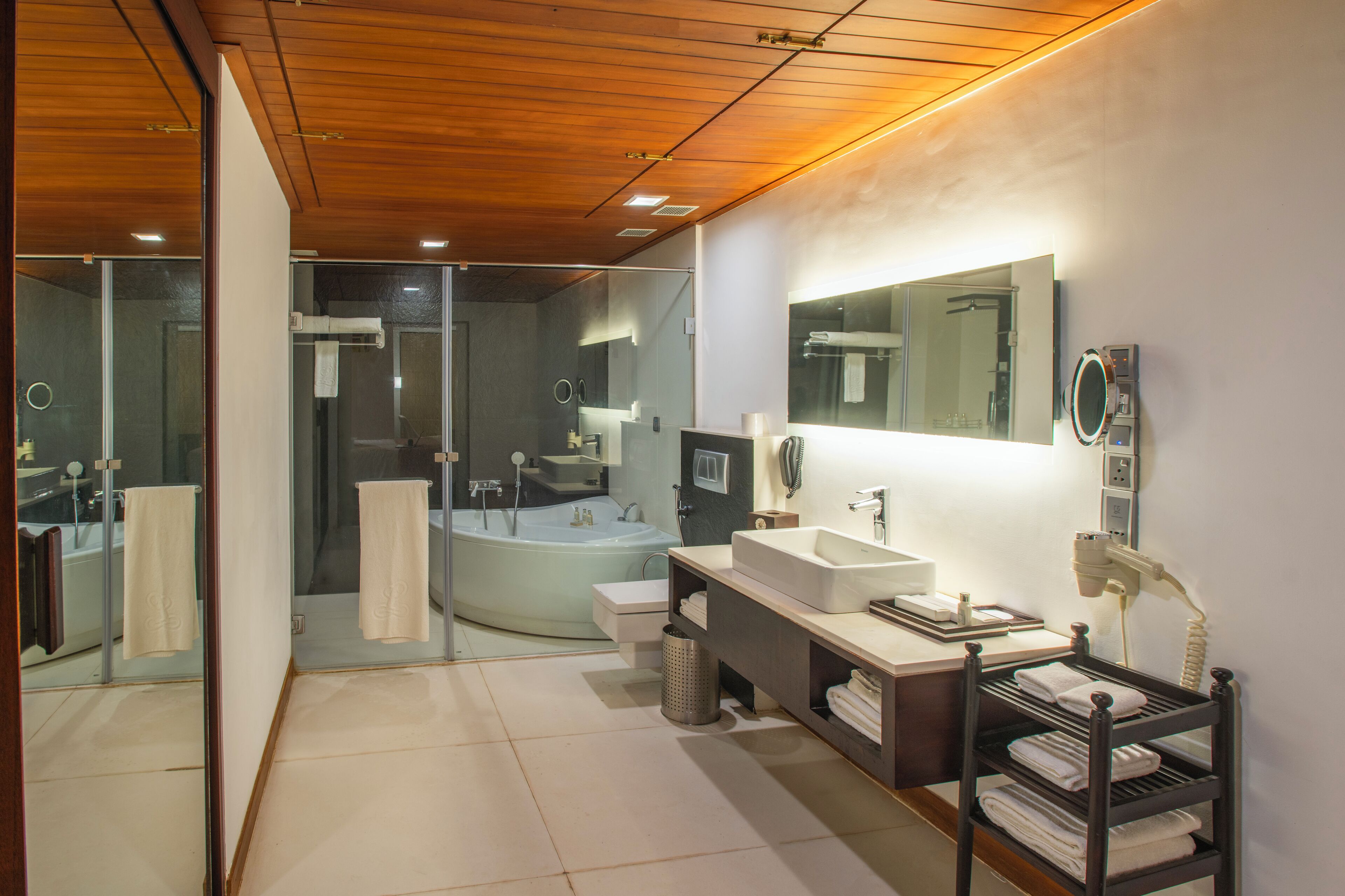 A modern bathroom with a large bathtub, two sinks, a vanity, and a mirror.