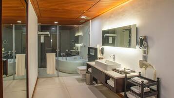 A modern bathroom with a large bathtub, two sinks, a vanity, and a mirror.