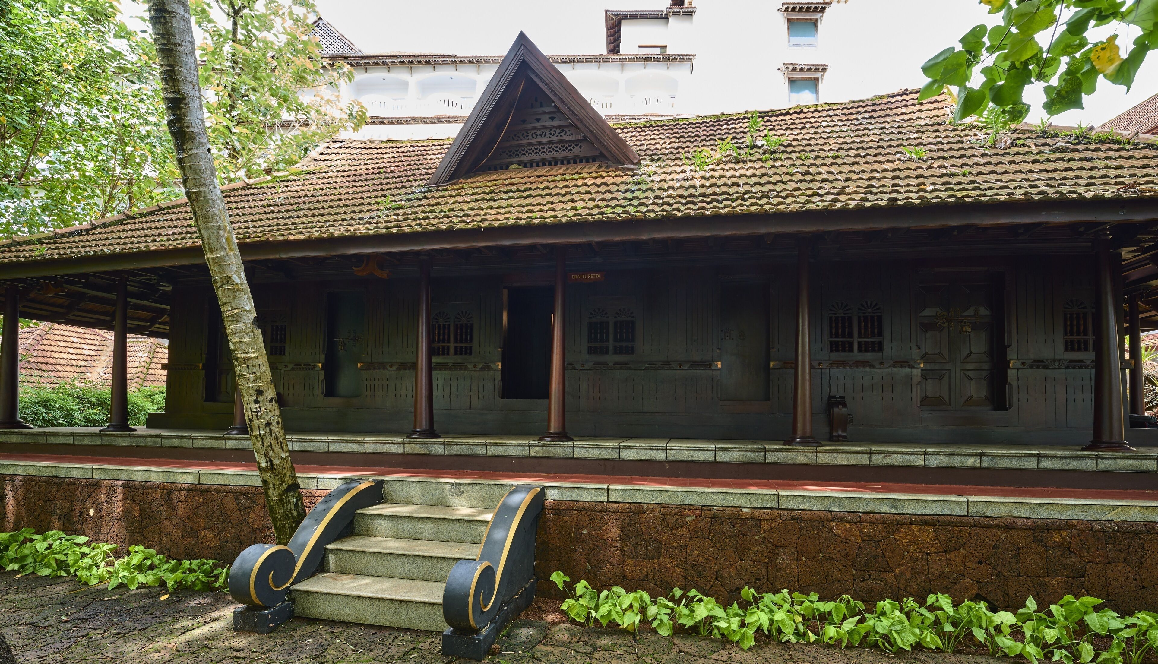 A traditional building with a tiled roof, a covered porch, and a stone wall.