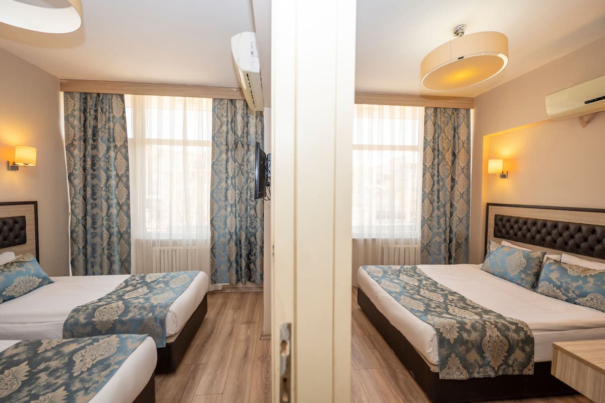 Une chambre d’hôtel avec deux lits, une télévision, un ventilateur de plafond et une fenêtre avec des rideaux.
