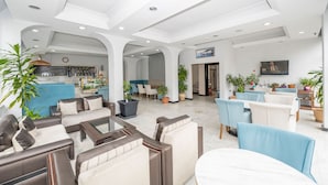 A spacious lobby with modern furniture, a bar area, and potted plants. - Tugra Hotel (Istanbul)