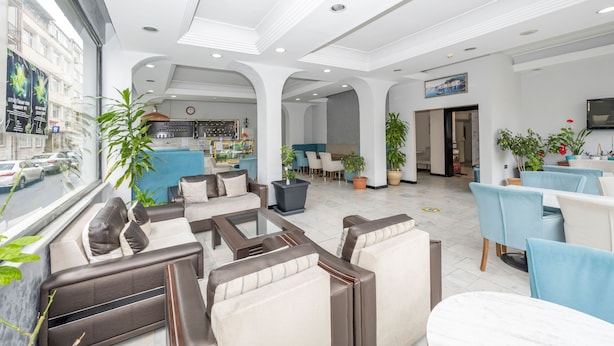 A spacious lobby with seating areas, a bar, and potted plants. - Tugra Hotel (Istanbul)