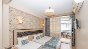 A hotel room with two beds, a large window with curtains, a TV mounted on the wall, and a ceiling fan. - Tugra Hotel (Istanbul)
