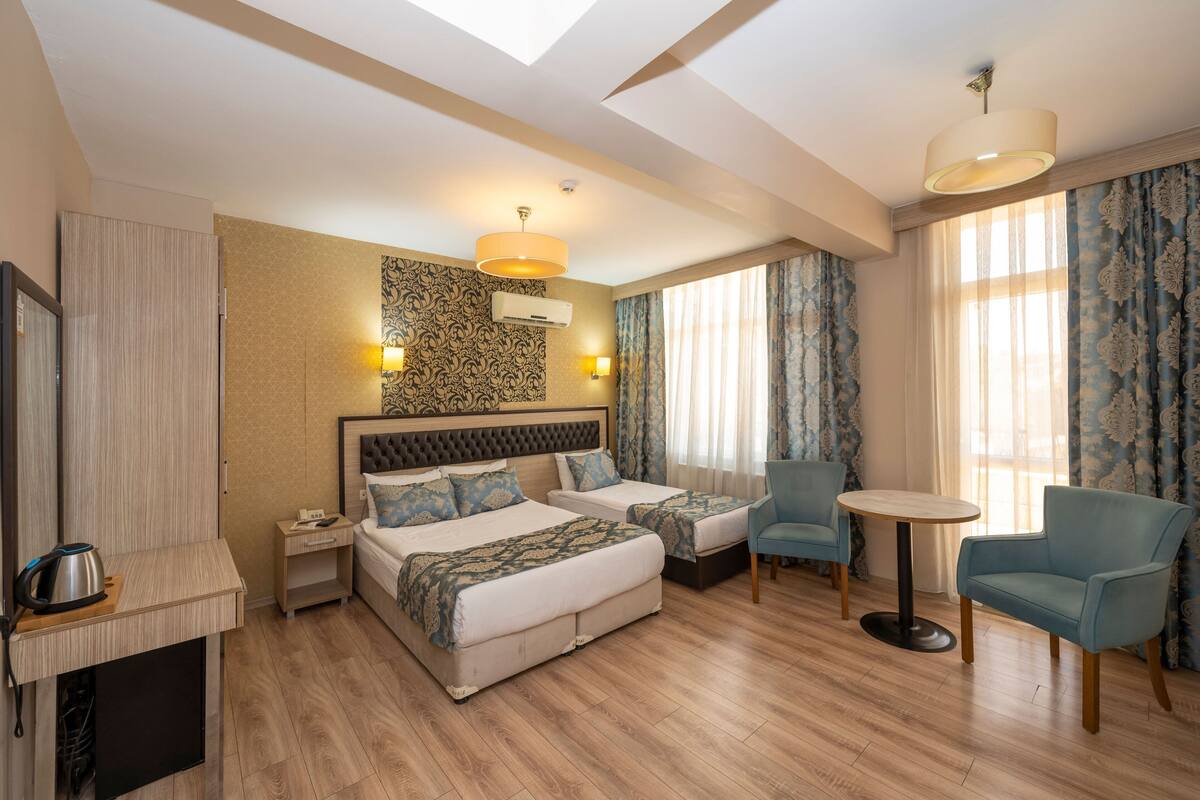 Une chambre d’hôtel avec deux lits, une petite table, une chaise, un téléviseur et une armoire.