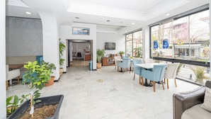 A modern lobby with a reception desk, seating area, and large windows offering a view of the street. - Tugra Hotel (Istanbul)