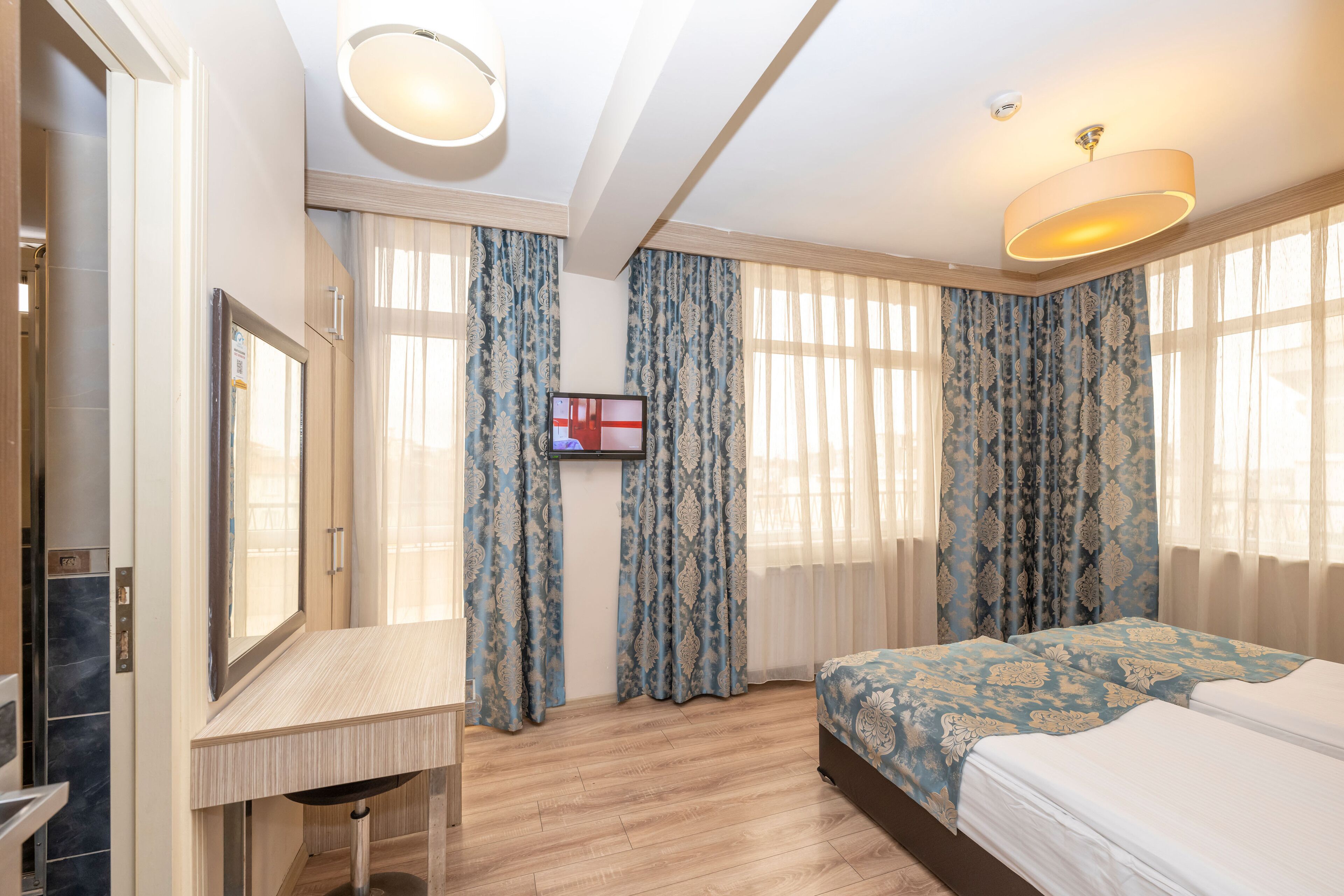 A hotel room with a bed, a desk, a television, and a bathroom.