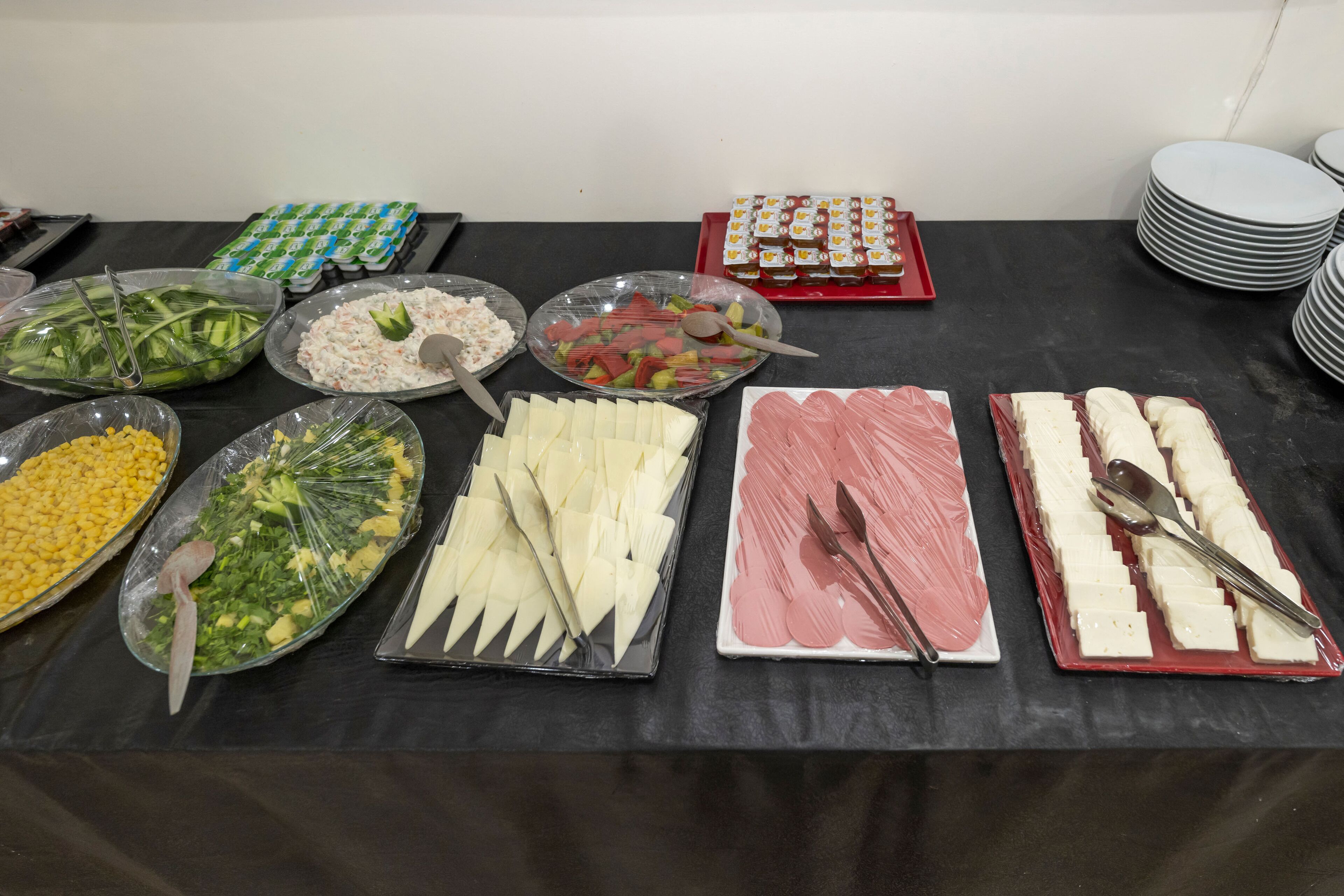 A buffet table with various food items including salads, cheeses, and meats.