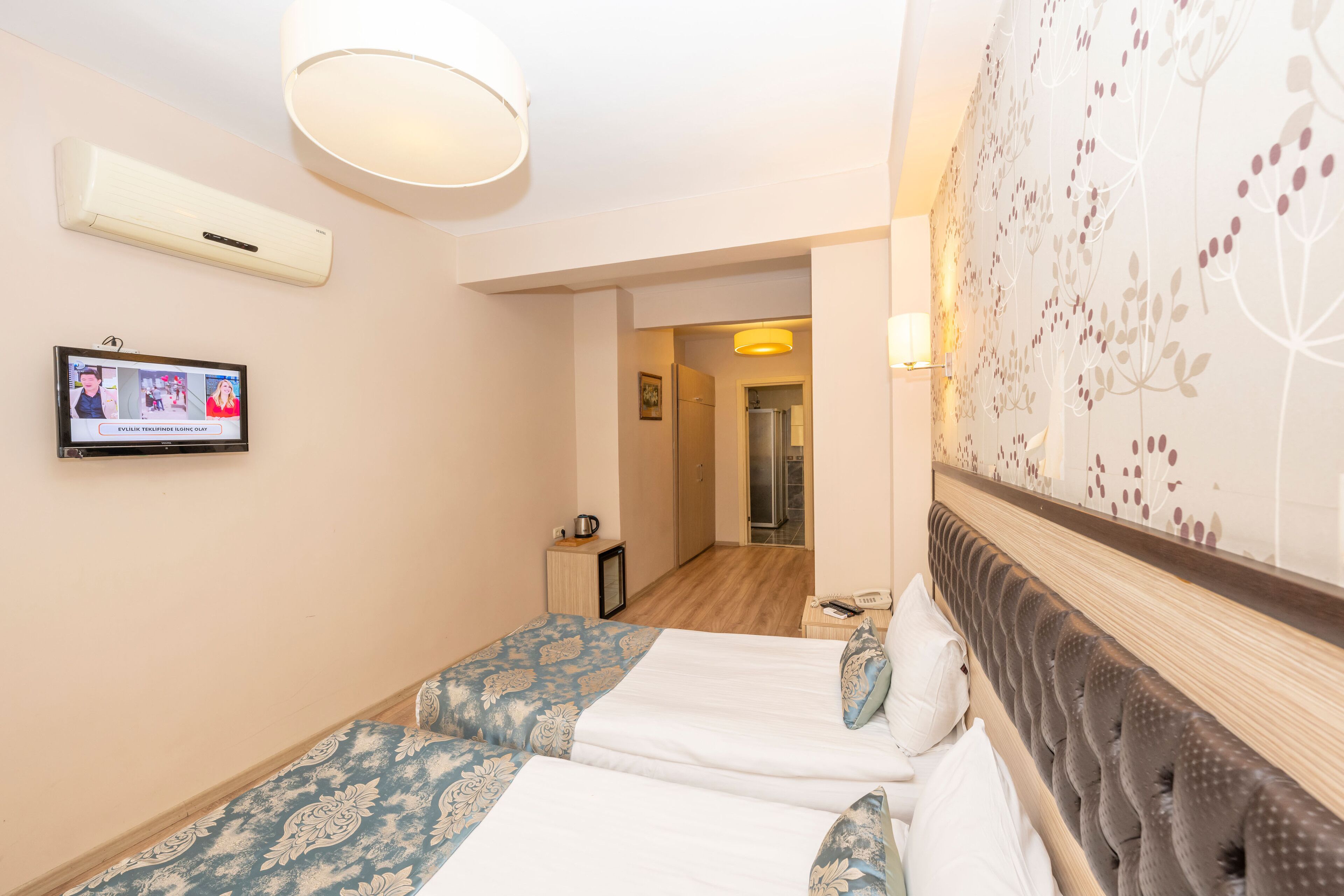 A hotel room with two beds, a TV mounted on the wall, and a decorative wall panel.