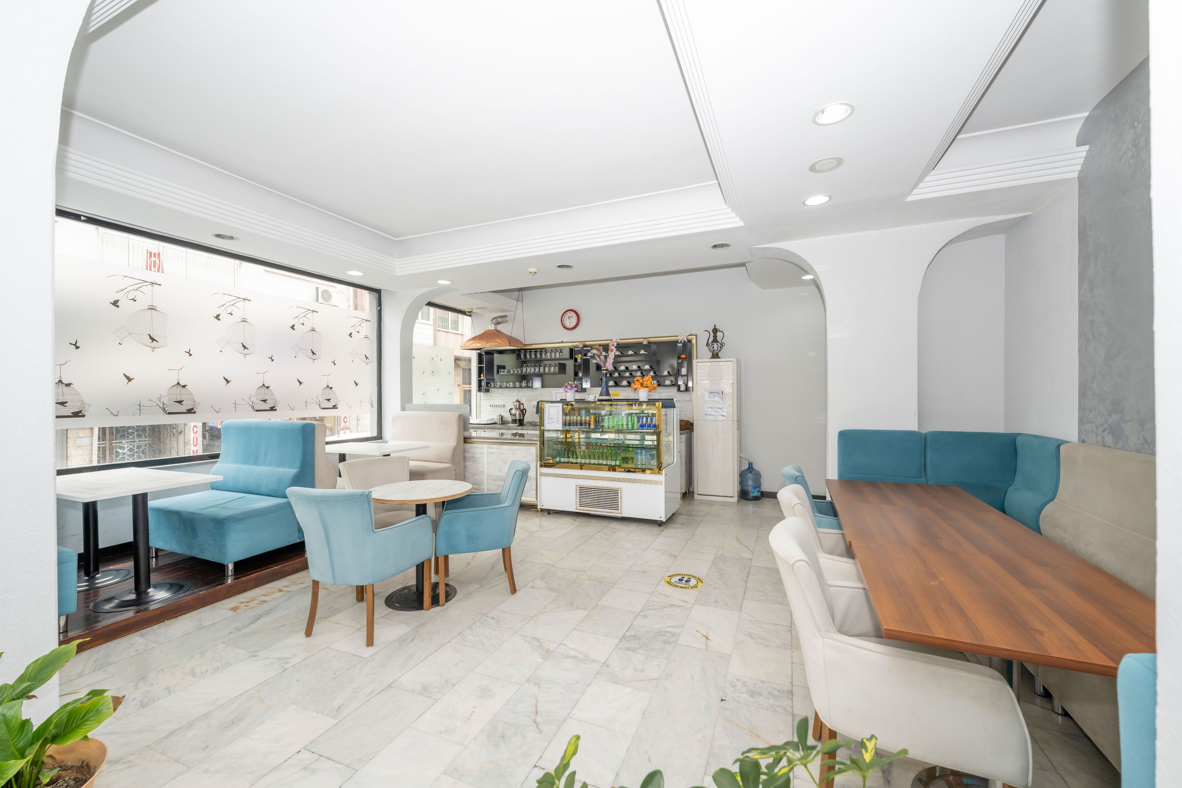 A modern cafe with blue and white seating, a coffee machine, and a display case with beverages.