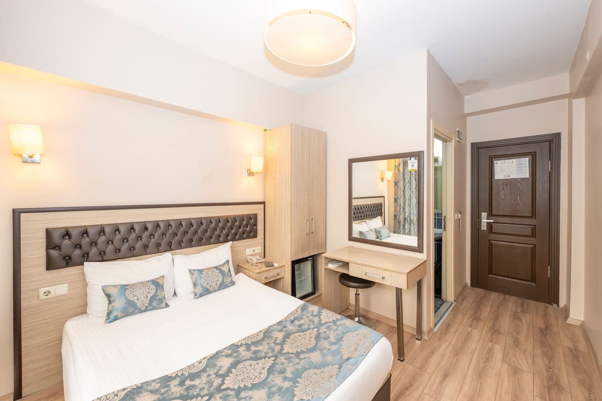 Une chambre d’hôtel avec un grand lit, un bureau, un miroir et une porte.