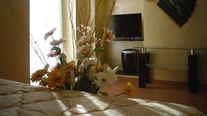 A bedroom with a bed, a vase of flowers, a TV, and a decorative fan. - Via Palazzo Sanremo (Sanremo)