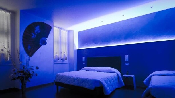 A modern hotel room with a large bed, a bedside table, and a wall-mounted fan. - Via Palazzo Sanremo (Sanremo)