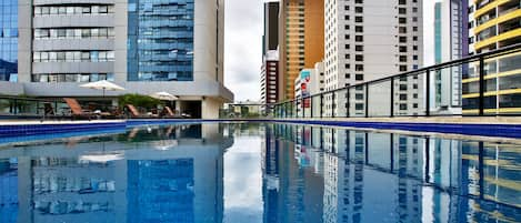 Una piscina al aire libre, sillones reclinables de piscina