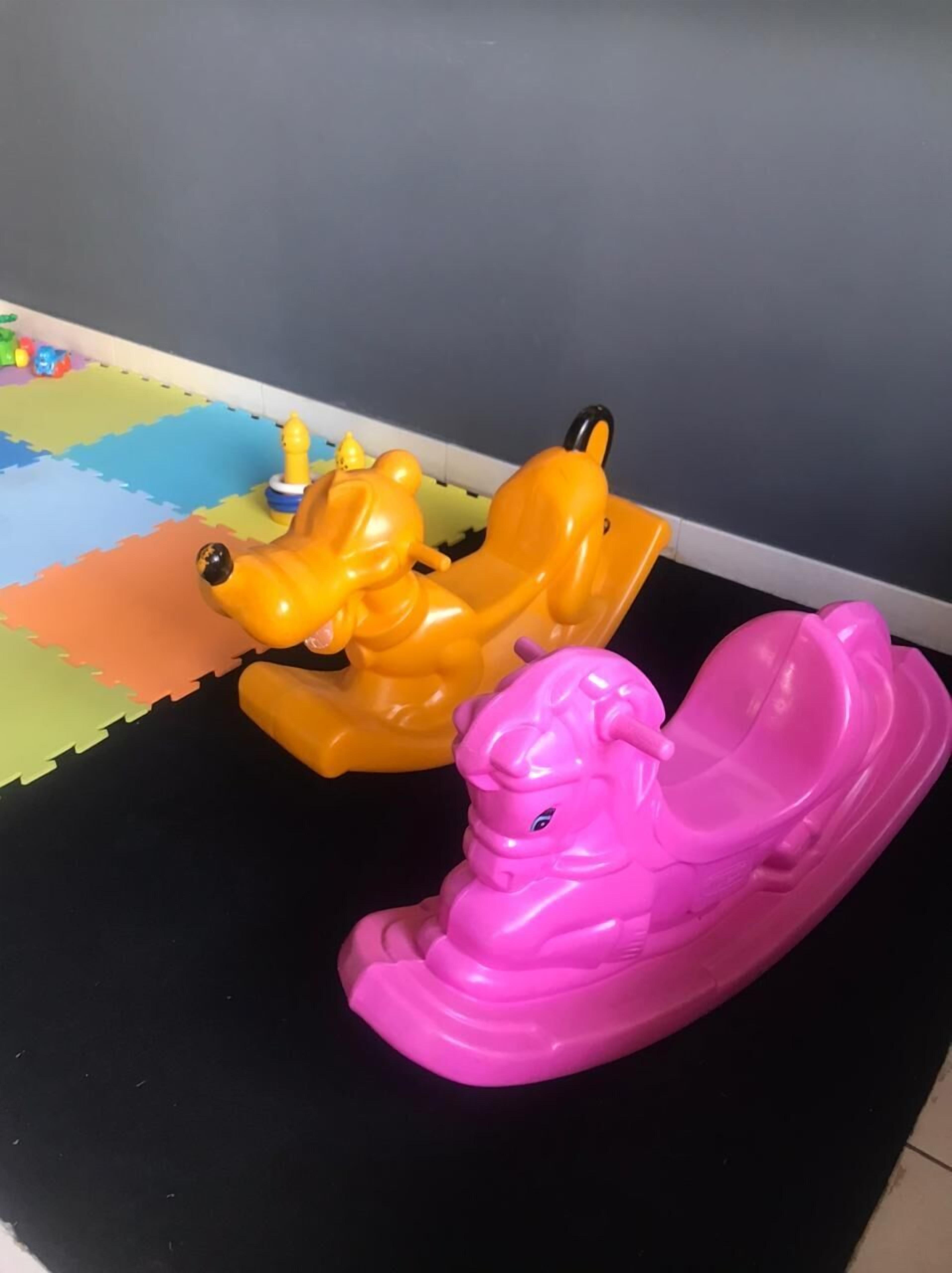 Two toy elephants on a black floor with colorful foam mats in the background.
