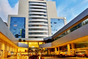 Ein modernes Hotel mit Glasfassade, einem zentralen Atrium und einer Dachterrasse.