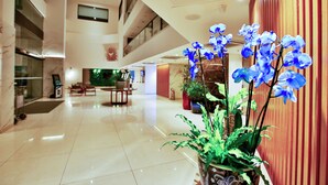 Eine geräumige Lobby mit hoher Decke, einer zentralen Sitzecke und Zimmerpflanzen.