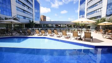 Een buitenzwembad, ligstoelen bij het zwembad