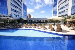 Una piscina al aire libre, sillones reclinables de piscina