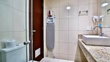 A bathroom with a sink, mirror, and ironing board.